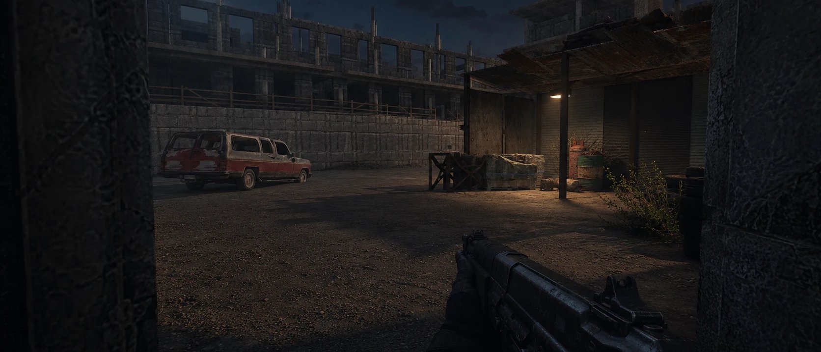 First-person view into the yard at night: a rusted red SUV, an unfinished concrete frame and a lamp over the sheds